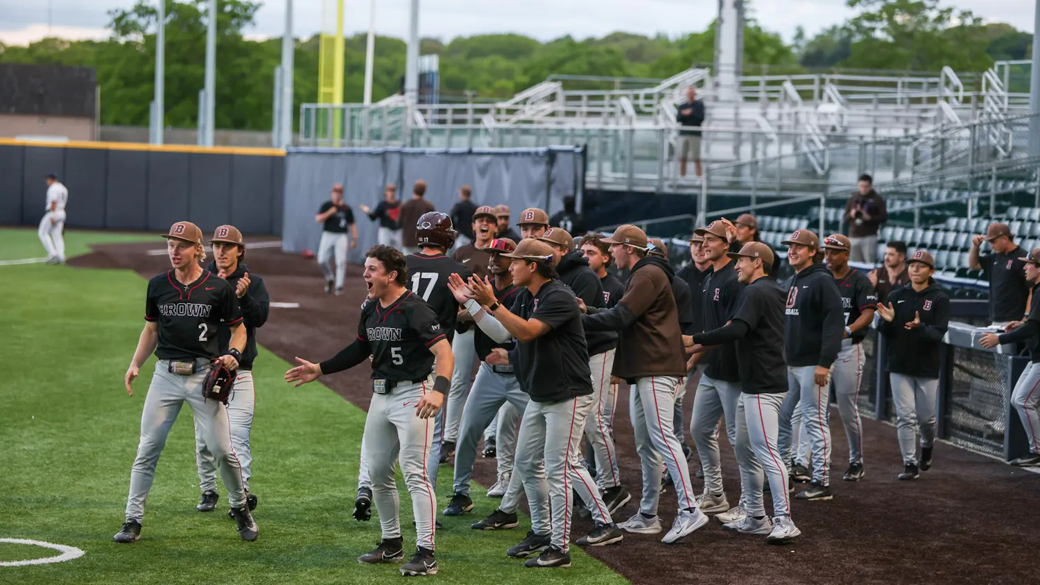 Baseball team emerges from the dugout in celebration, screaming and clapping hands.